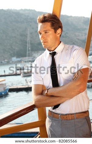 handsome man in a white shirt looking away, sunshine outdoors, sea port