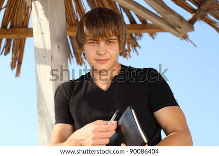 Handsome young man with writing pad, outdoors