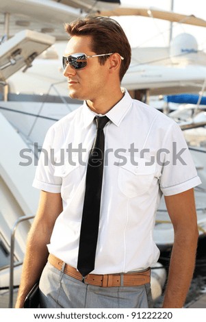 Man captain in a white shirt near the yacht, looking away