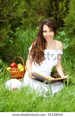 Smiling beautiful woman read the book on the nature. garden