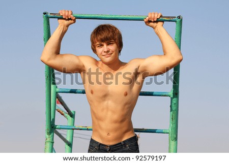 Young athletic man  holding on to horizontal bar, outdoors