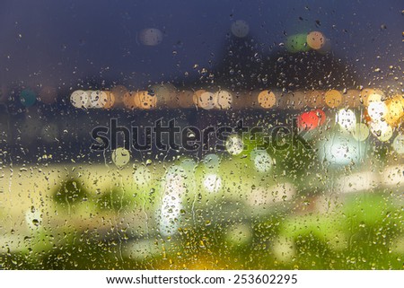 Drops of rain on window with abstract lights out of focus