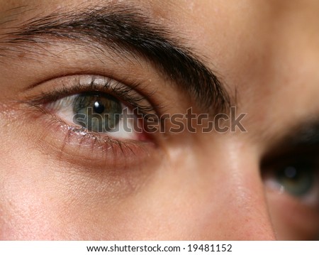 Closeup of green eyes of young man with a serious look on his face