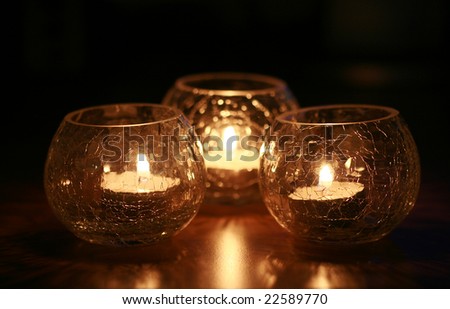 three beautiful glassy candle holders with burning tea candles