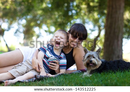 Excited toddler with his mother and dog in a park