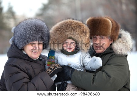 Happy grandparents with a cute toddler boy in their arms on a cold winter day