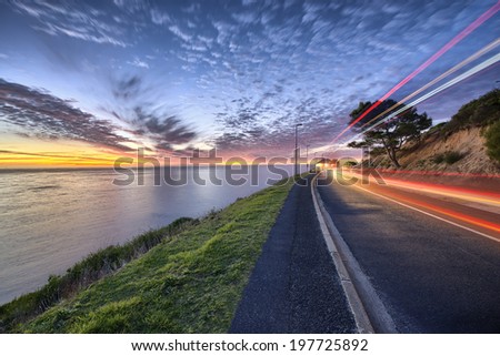 Cape Town sunset over ocean and road to the right with cars passing by shown with colorful streaks of light