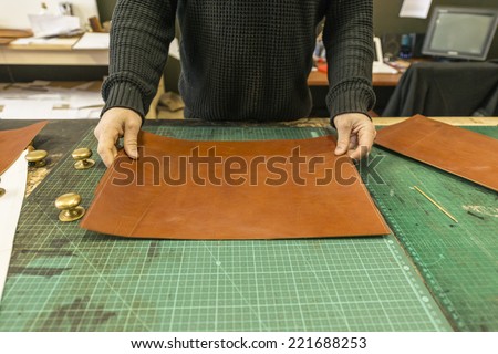 Factory workers, creating hand made leather bags and wallets in a leather workshop with tools