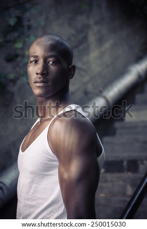 Sad black, african american man, thinking against a concrete wall, wearing vest shirt
