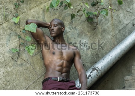 Sad black, african american man, thinking against a concrete wall, wearing no shirt