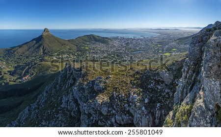 View from one of the many hiking routes up Cape Town\'s Table Mountain. Lions Head and Cape Town city in distance as sun rises over the city. Very popular daily activity for both locals and tourists.