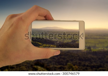 Tourist hand holding smart phone, taking photo of Auckland New Zealand, Mt Maunganui