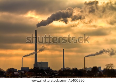 Winter scenic of power plant with a burning yellow sky behind