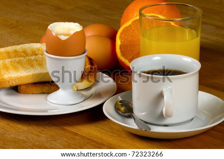Breakfast: Boiled egg, toast, coffee and fresh orange juice. On Wooden table