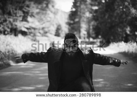 young man with arms outstretched on the road black and white photography