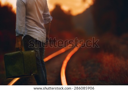 a man with a suitcase on the railroad