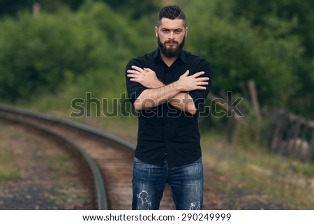 young beautiful young man standing on a railway line