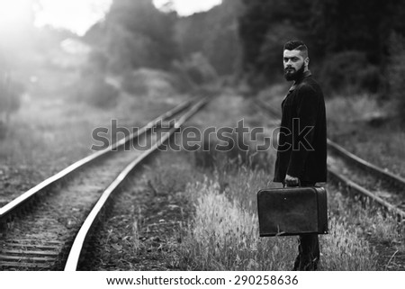 a young man with a suitcase on a railway line black and white photography