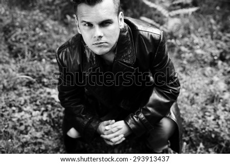 young man crouching black and white photography