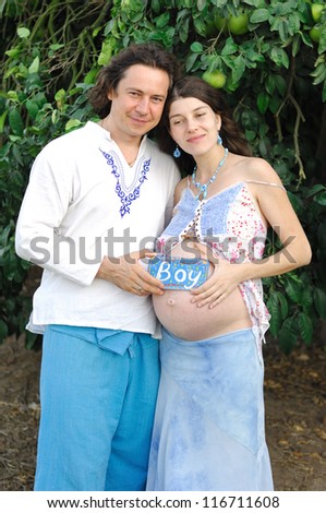 Young happy pregnant woman & her husband in the country clothes
