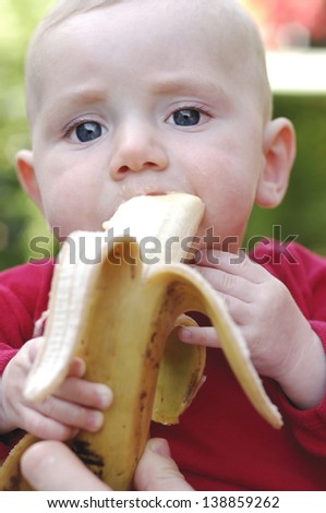 Sweet baby boy eat banana outdoor