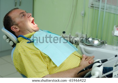 patient with the opened mouth in chair of dentist