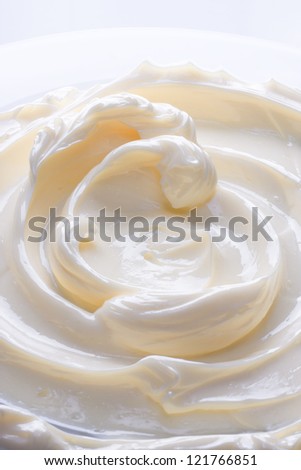 Swirling surface of light beige low-fat milky cream. Close-up photo.