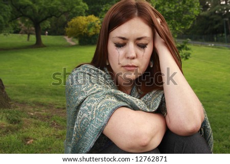 A girl in tears. Emotions of a young woman sitting alone in a garden.