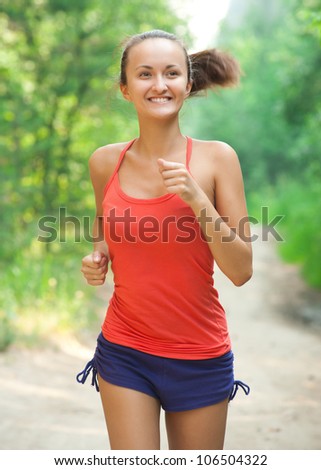 Young beautiful caucasian woman jogging in summer park. Woman in sport outdoors