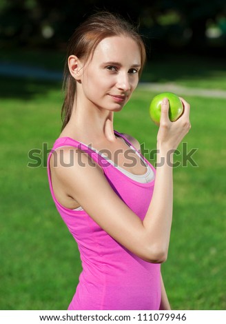 Young beautiful caucasian woman after sport workout eating apple outdoors