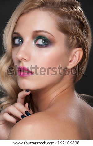 Close-up studio portrait of young beautiful woman with bright fashion makeup and manicure