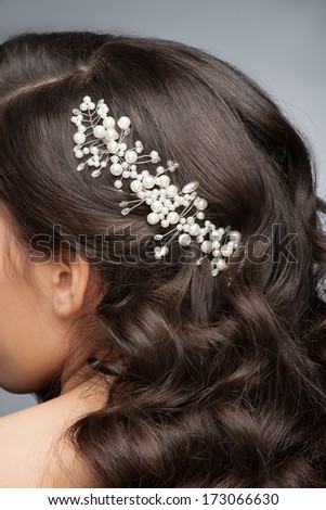 Closeup of brown hair with stylish pearl hair accessory, rear view