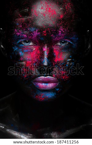 Portrait of beautiful girl with bright fashion art makeup with black face . Over black background