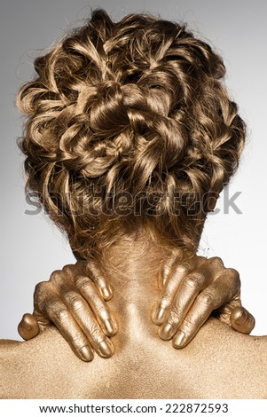 Portrait of beautiful woman with golden bodyart and hairstyle with braids