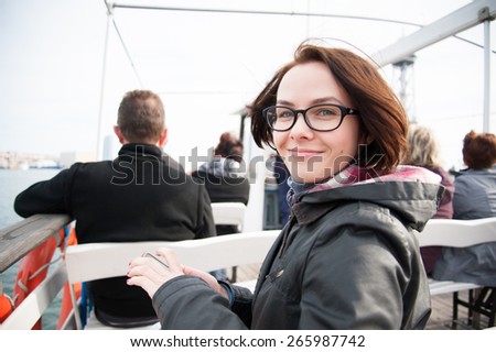 Young woman sitting on boat, looking at camera and smiling