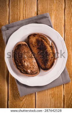 Burnt toast bread on the plate, on wooden table background