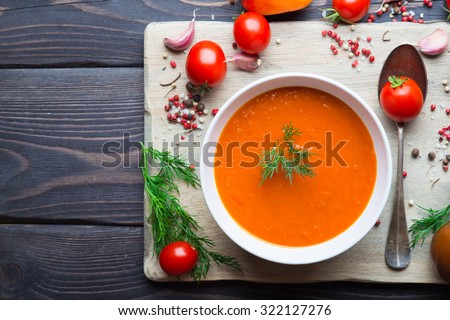 Tomato soup and fresh tomatoes on a wooden background