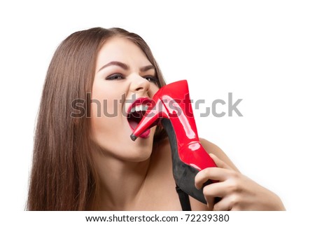 Portrait of pretty young woman with bright make-up biting her red shoe, over white background