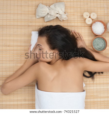Beautiful young woman lying on bamboo mat at spa salon and relaxing