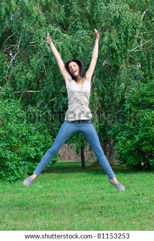 Happy young woman jumping in air with arms extended outdoors