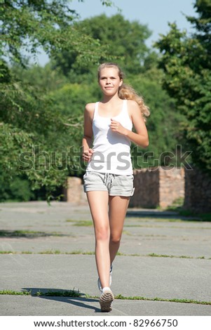 Young beautiful woman jogging in summer park