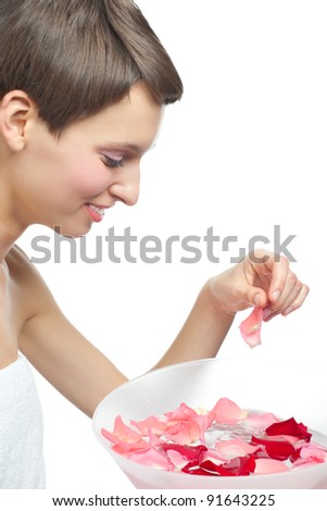 Portrait of a pretty young woman going to wash her face with water. Girl holding rose petal in her hand and smiling