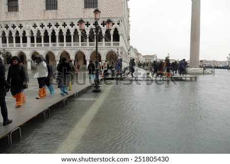 Venice, 6 February 2015. After heavy rain and strong wind, the water level rose by over 1 meter. Piazza San Marco is under water. Tourists run on platforms.