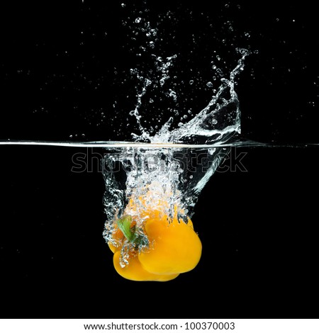 Fresh yellow paprika splash in water on black background