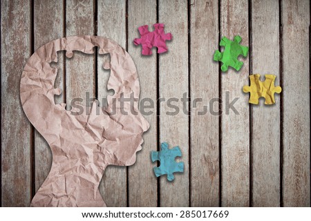colorful jigsaw puzzle pieces and wrinkled paper project as a outline of children head on wood background