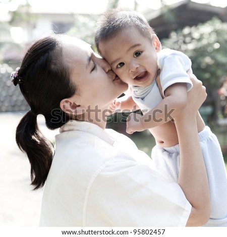 Asian mom kissing her son