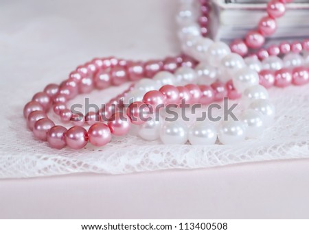 White and pink pearl necklace on top of books
