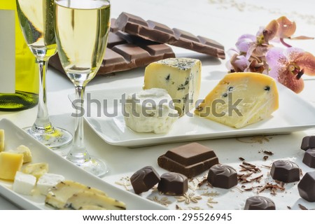 Cheese, chocolates, wine, and orchid on white