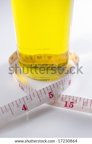 Studio shot of olive oil and measuring tape against white background