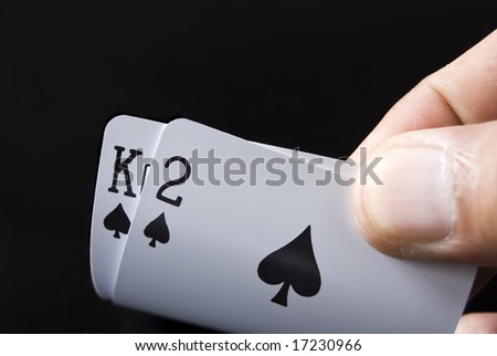 Blackjack cards held by hand against black background
